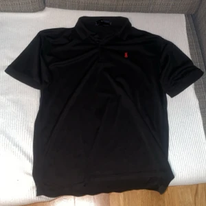 Piké tröja - Ralph lauren liknande piké tröja i storlek L men sitter lite mindre, mer som storlek M. Färgen är svart med röd logga. Den är bara provad ej använd!