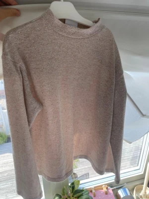 Beige stickad tröja med pärlor Zara - Supersöt beige stickad tröja från Zara med små guldfärgade pärlor över hela tröjan. Tröjan har en högre rundad hals och långa ärmar. Perfekt för dig som gillar en enkel men ändå glittrig look.