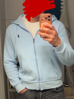 Ralpha lauren kofta  - Snygg ljusblå hoodie från Polo Ralph Lauren med dragkedja framtill och två fickor. Klassisk huva med dragsko och den ikoniska loggan broderad på bröstet. Perfekt för en avslappnad och stilren look.