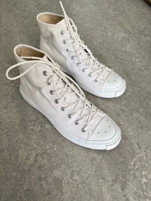 Vita höga sneakers i canvas acne studios - Säljer ett par klassiska vita sneakers i canvas med högt skaft och vita snören. Skorna har metallfärgade öljetter och vit gummisula med tåhätta. Perfekta för en clean och stilren look.