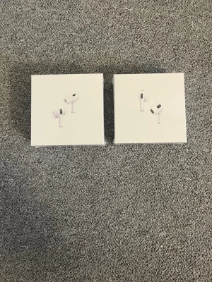 Apple AirPods Pro med laddningsetui - Säljer två par Apple AirPods Pro i originalförpackning. Trådlösa in-ear hörlurar i vit färg med laddningsetui. Snygg och kompakt design i plast, perfekt för musik, samtal och träning. Levereras i stilren vit box med Apple-logga.