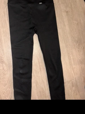 Svarta träningsbyxor från Stronger - Snygga svarta tränings tights från Stronger med hög midja och stretchigt material. Perfekta för träning eller chill dagar. Diskret logga framtill i midjan och smal passform som sitter skönt på kroppen. I storlek L men passar mer på M