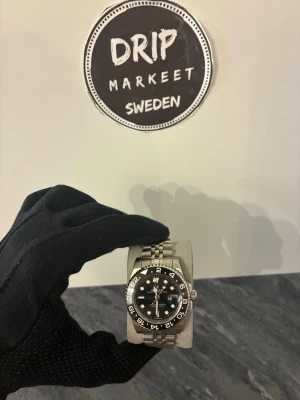 ROLX GMT MASTER ||  - Snygg klocka i rostfritt stål med saphir glas och index visare med extra länkar och klock skruvmejsel . Klockan har tydliga siffror runt boetten och klassisk design som passar till många olika stilar. Perfekt accessoar för dig som gillar en clean look.