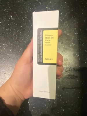 COSRX Advanced Snail 96 Mucin Essence - COSRX Advanced Snail 96 Mucin Power Essence är en toner i en vit rektangulär förpackning med gul och svart etikett. Innehåller 100 ml och är känd för sin återfuktande och reparerande formula med snigelsekret. Perfekt för dig som vill boosta din hudvårdsrutin.