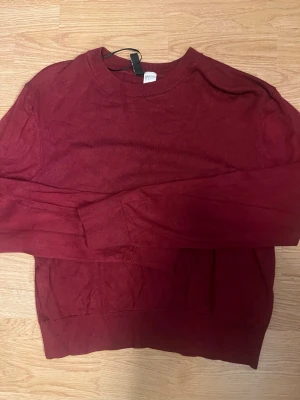 Vinröd stickad tröja från H&M Divided - Mysig vinröd stickad tröja från H&M Divided i storlek S. Tröjan har rund halsringning, långa ärmar och ribbade muddar vid ärmslut och nederkant. Perfekt för lager på lager och enkel att matcha med olika outfits.