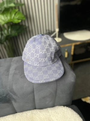 Ljuslila keps med GG-mönster - Snygg ljuslila keps från Gu cci med det klassiska GG-monogrammet över hela kepsen. Kepsen har böjd skärm och är tillverkad i ett tygmaterial som ger en exklusiv känsla. Perfekt accessoar för att lyfta din outfit.