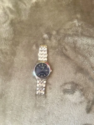 Citizen silverklocka med blå urtavla - Snygg klocka från Citizen med silverfärgad länk och en stilren blå urtavla. Klockan har datumvisning och klassisk rund form. Perfekt accessoar för dig som vill ha en elegant och tidlös look. Nypris ≈2100kr