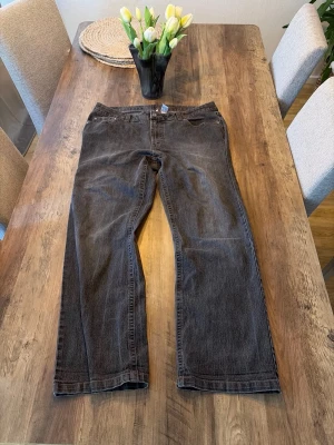 Bruna raka jeans med fem fickor - Säljer ett par grå jeans med rak passform och klassisk femficksdesign. Jeansen har normal midja och är tillverkade i ett slitstarkt denimtyg. Perfekta för en avslappnad och stilren look.