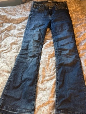 Nelly jeans - Snygga blå bootcut jeans med låg midja och klassiska fem fickor. Jeansen har en lätt utsvängd passform nertill och är gjorda i denim. Perfekta för dig som gillar en retroinspirerad look och vill ha ett par jeans som sticker ut lite extra.