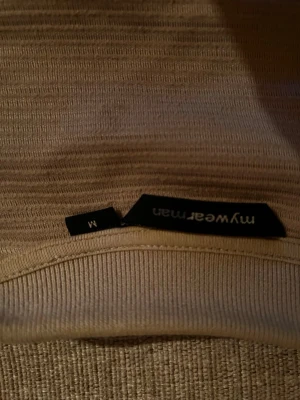 Beige ribbad tröja från mywear man - Säljer en beige ribbad tröja från mywear man i storlek M. Tröjan har en enkel och stilren design med rund hals och långa ärmar. Perfekt att matcha med jeans eller chinos för en clean look.