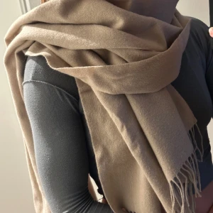 Halsduk - Stor halsduk i fin kall, beige färg. Fransar på ändorna. 