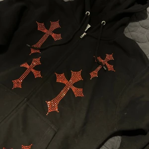 Red Rhinestuds cross zip up - Helt ny, har aldrigt använt den köpte den på mistag för 750kr. Storlek M passar till tjej och kille.