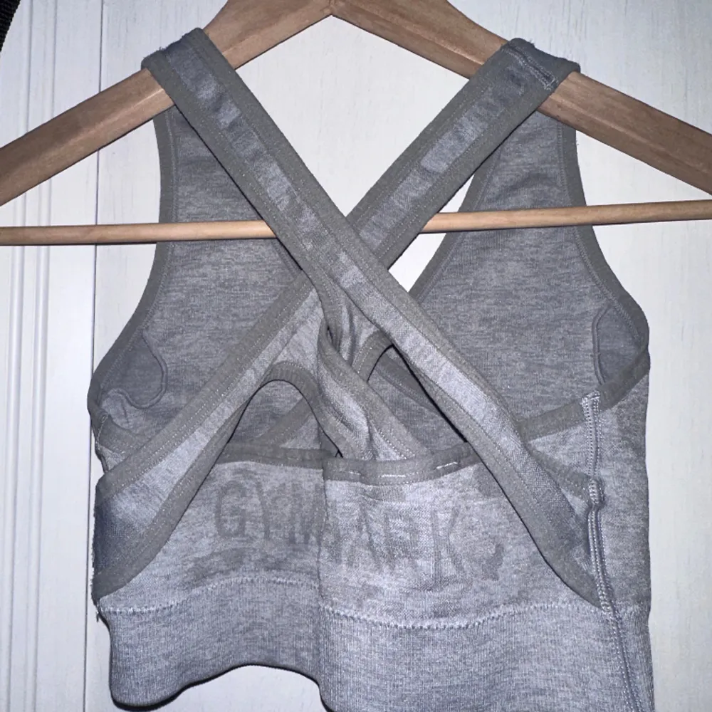 Tag size S, but RUNS SMALL!!!! I wrote XS, but the tag is S. Please be very aware of this sizing. Grey sports bra with back cut outs and pad inserts. Logo print slightly cracked. Gently used condition with some fuzz. . Toppar.