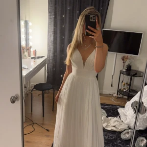 Vit balklänning  - Vit balklänning från Pure White by lily - en brud och balklännings butik i Stockholm. Skydd runt klänningen tillkommer. Klänningen är uppsydd hos skräddare nertill samt banden runt axlarna. Precis vid kanten av brösttyget finns spår av smink (tvätt).