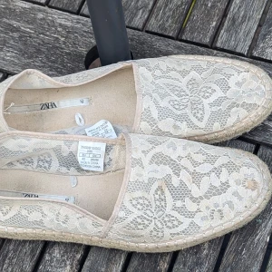 Beige spetsiga loafers från Zara - Ett par beige loafers från Zara med spetsdetaljer. Skorna har en platt sula och är dekorerade med ett blommigt spetsmönster.I fint skick, sparsamt använd men det behöver rengöras från fläckar vg och se bilder 