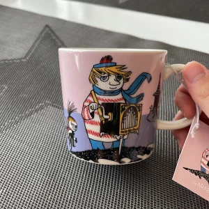 Muminmugg Too-Tiky - En muminmugg från arabia med Too-Tiky motiv. Helt oanvänd med lapp kvar, säljer pga dublett. Har en liten fläck där färgen är avskavd som produktionsfel men annars är den som ny.