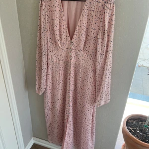 Adoore klänning Paris - Klänning ifrån Adoore med blommigt mönster och knappar framtill. Storlek 36, använd vid ett tillfälle så den är i nyskick. Lappen finns kvar med tillhörande extra knapp och tråd.   Nypris: 1495kr