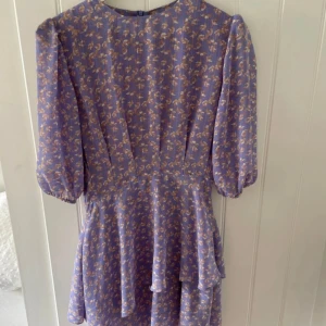 Fin klänning från Adoore  - Adoored Asymmetric lilac dress i storlek Large (storlek 40). Färg/mönster som inte längre säljs! Använd endast vid ett tillfälle.