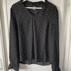 Svart vitprickig blus - Fin svart blus med vita prickar. Använd. Inte stretchig. I bra skick. 