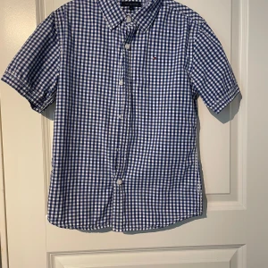 Skjorta från Tommy hilfiger - En fin skjorta från Tommy hilfiger i bra skick för barn 12 år. Den är använd men ändå i fint skick och inga tecken på skador.