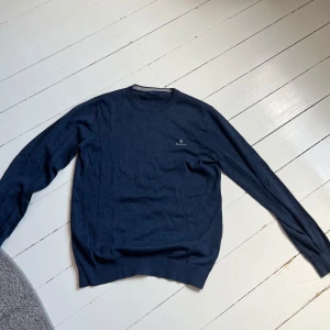 Stickad tröja GANT - Säljer min mörkblå stickade tröja från GANT som jag inte använder längre, den är i grymt skick med inga skador eller slitningar 