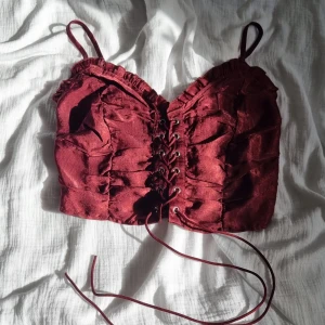 Sommartopp med snörning  - Röd med lite lila i färgen. Snörning i mitten och justerbara band. Väldigt stretchig. 