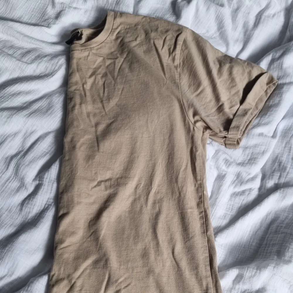 Beige basic t-shirt. Vikta ärmar som är sydda så de åker inte ner. . T-shirts.