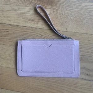 Rosa plånbok - En rosa plånbok med dragkedja i bra skick. Plånboken är ungefär 10 x 20 cm. Minns inte vart den inhandlades. 