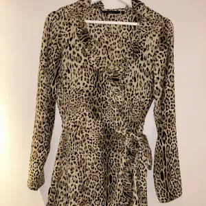 Omlott klänning med snörning på sidan. Leopard mönster. Köpt för ca 3 år sedan, minns ej vart, står Amelie & Me på lappen. 