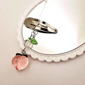 Metallhårspänne med blad och en peach och genomskinlig glaspärla. 