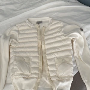 Moncler cardigan - Hej! Säljer min systers gamla moncler cardigan i storlek S som blev för liten för henne, inga fläckar, ett litet hål i tyget som knappt syns annars är den 9:10 skick.