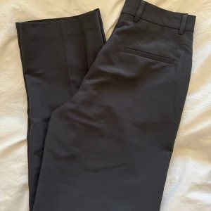 Kostymbyxir - Raka gråa kostymbyxor med hög midja. De passar inte mig så kan inte skicka bild med byxorna på tyvärr. Aldrig använda