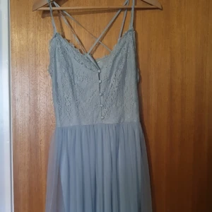 Blå långklänning  - Vet inte exakta måttet då lapparna är avklippta men ca 38-42 skulle jag säga. Använd enstaka gången och är i bra skick. Perfekt att ha på midsommar eller andra högtider. Lång babyblå klänning med spets och tyll.