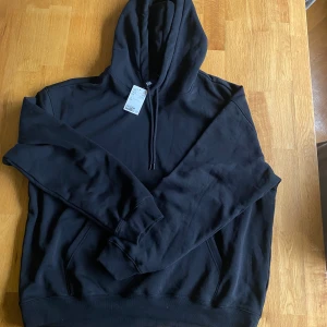 Oanvänd H&M hoodie  - Nyskick med prislappen kvar. Oversized relaxed fit hoodie som är helt svart utan tryck. 