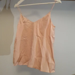 Ljusrosa linne i skimmrande tyg - Rosa linne i ett mjukt skimmrande fint tyg. Perfekt till fest! Använd 2 gånger så i riktigt bra skick. Fina kors-detaljer vid ryggen. Storlek 36 så passar XS-S 💕 pris kan diskuteras 