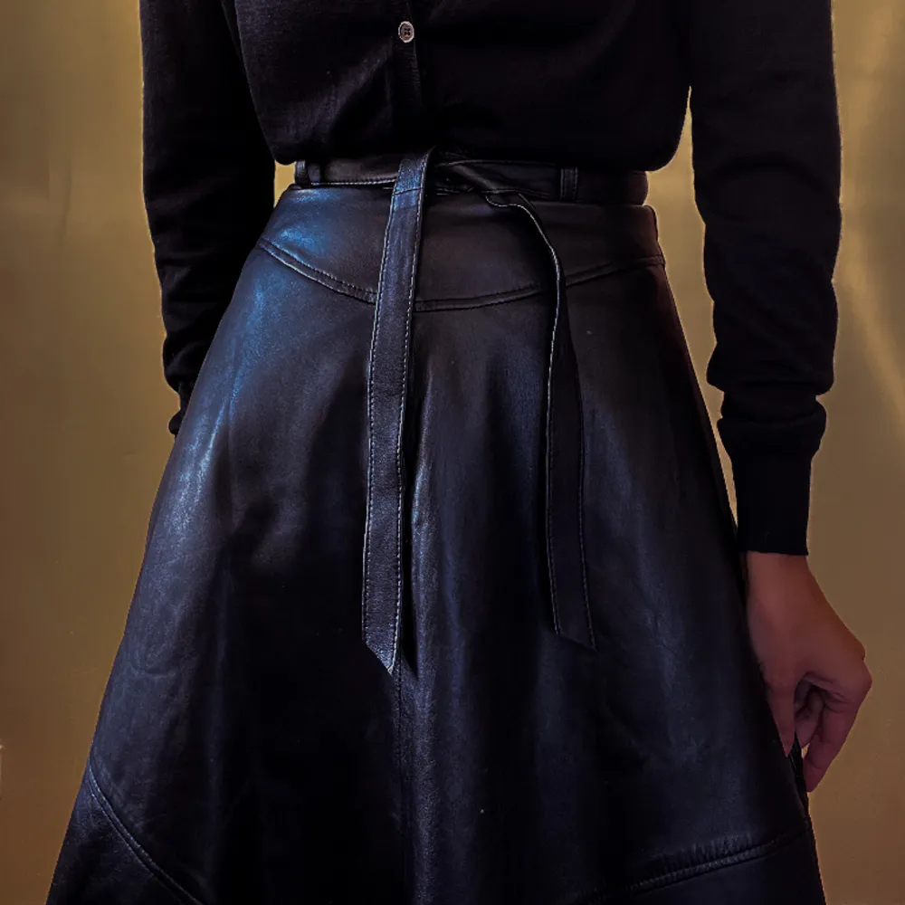 Vintage knee length leather skirt with raw hem. Back Zip Closure and Detachable Leather Belt, Fully lined. Feminine silhouette  Very Good Condition   Model Is 160cm (5'3