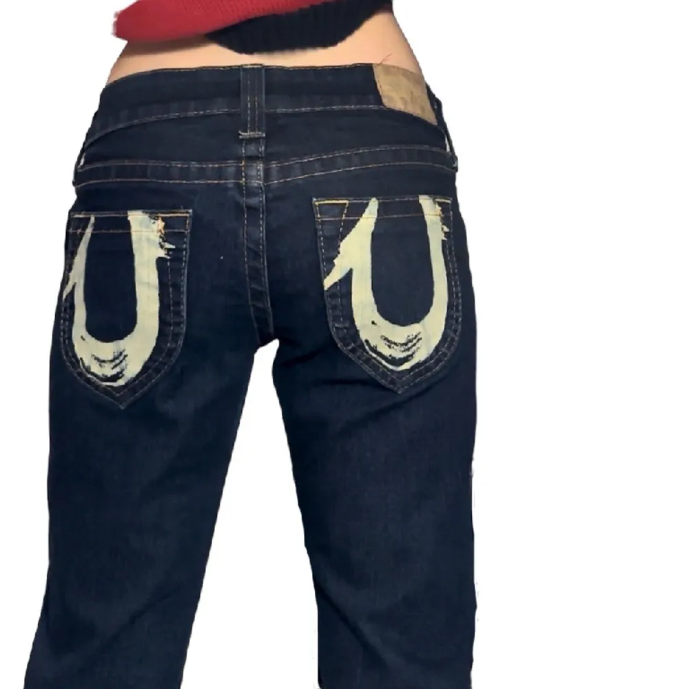 Säljer ett par jättecoola lågmidjade raka/lite baggy True Religion jeans med coola tryck på fickorna bak, storlek 28 så passar storlek S, jag har XS på bilden, jättebra skick då de knappt använda, från 2000 talet. Jeans & Byxor.
