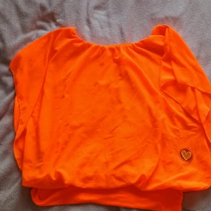 Orange topp - En neon orange topp i "one size" med ett litet hjärta längst ner. Super fint skick trotts användning under "70 tals fest". Så perfekt för sånna tema fester 