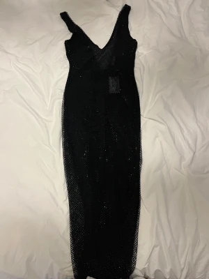 Svart klänning - En svart midiklänning. Klädd i ”diamanter”. Något genomskinlig men funkar perfekt med svarta underkläder! Passar en XS-S. Aldrig använd. Köpt för ca 1900 kr. Så fin men har tyvärr inte fått användning för den. Slut i svart på hemsidan (därav vita på bild)