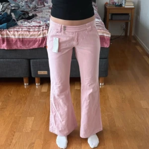Rosa jeans  - Rosa jeans, dubbelknäppning. Lågmidjade, bootcut. Lite för korta för mig som är 172 cm. Står på lappen att de passar om man är 164cm (sista bilden).  Ytterbenslängd: 97cm  Innerbenslängd: 76cm Midja: 39cm mätt platt Gren-midja:21cm Ny,prislappar kvar
