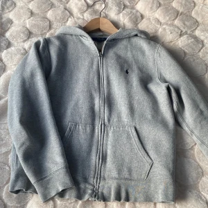 Ralph Lauren Zip Hoodie - Säljer denna gråa Ralph Lauren Zip hoodie. Den är i storlek L 14-16 i barnstorlek. Men det motsvarar väl xs. Den passar förmodligen någon som är 170 helt perfekt. OBS Den är lite nopprig men det går att lösa hemma. Kom privat för mer info/bilder.