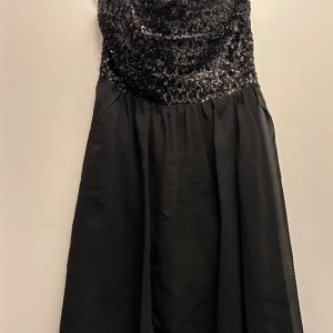 Klänning till nyår - Svart klänning i stl. M från Vila. Använd vid ett tillfälle så i mycket bra skick. Perfekt till nyår. Dragkedja i sidan och smock i ryggen. 