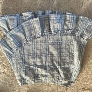 Rutig kjol - Rutig blå kjol med en volang. Passar storlek M