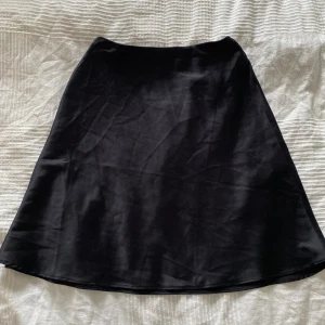 Kjol - Svart satinkjol med dragkedja vid sidan, aldrig använd!