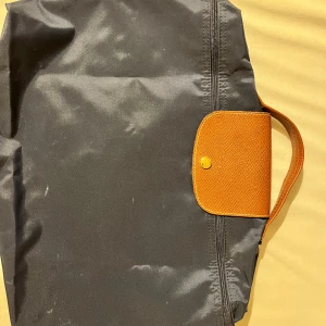 Longchamp Porte documents - Marinblå Longchamp Le Pliage Porte-Documents. Köpt i bryssel. Köpte för 100€(1150sek). I perfekt skick, används bara typ 2 gånger. Dimensioner är 37cm x 28cm x 8cm