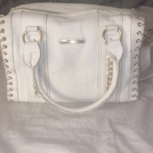 Vit väska  - Detta är en vit catwalk väska med guld detaljer. Väskan är lite sliten som syns på bilden men fortfrande fint skick och inget man tänker på! Väskan har även ett långt band som går att göra långt. Köpt för ungefär 1200kr