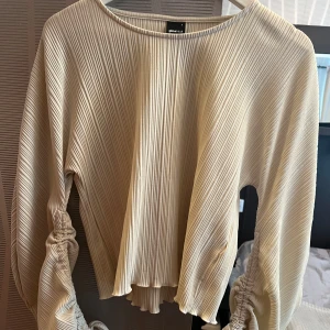 Beige ribbad blus  - Beige ribbad blus från Ginatricot med knytning på ärmarna. Storlek S. Fin skick.  