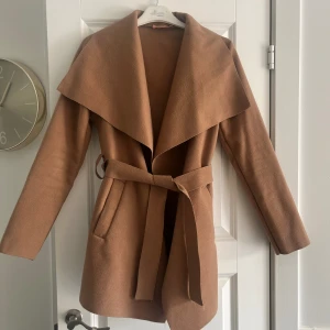 Kappa - En beige/brun kappa med knytning i storlek xs/s, endast använd i någon månad så den är som ny.