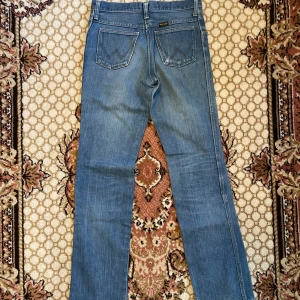 Wrangler blue Bell  - Straight Wrangler blue bell från 70 talet Väl använda men i bra skick  Storlek: längd 104 cm Midja 37 cm Benöppning 19 cm 