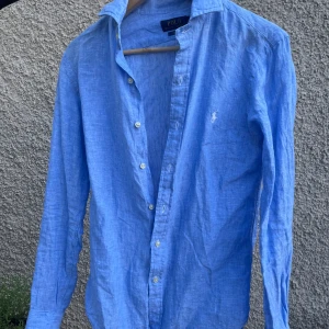 Ljusblå Ralph Lauren linneskjorta - Säljer min Ralph Lauren linneskjorta. Den är väldigt sparsamt använd utan ngr defekter. Perfekt för någon som är 170-180 lång och inte så kraftigt byggd. 